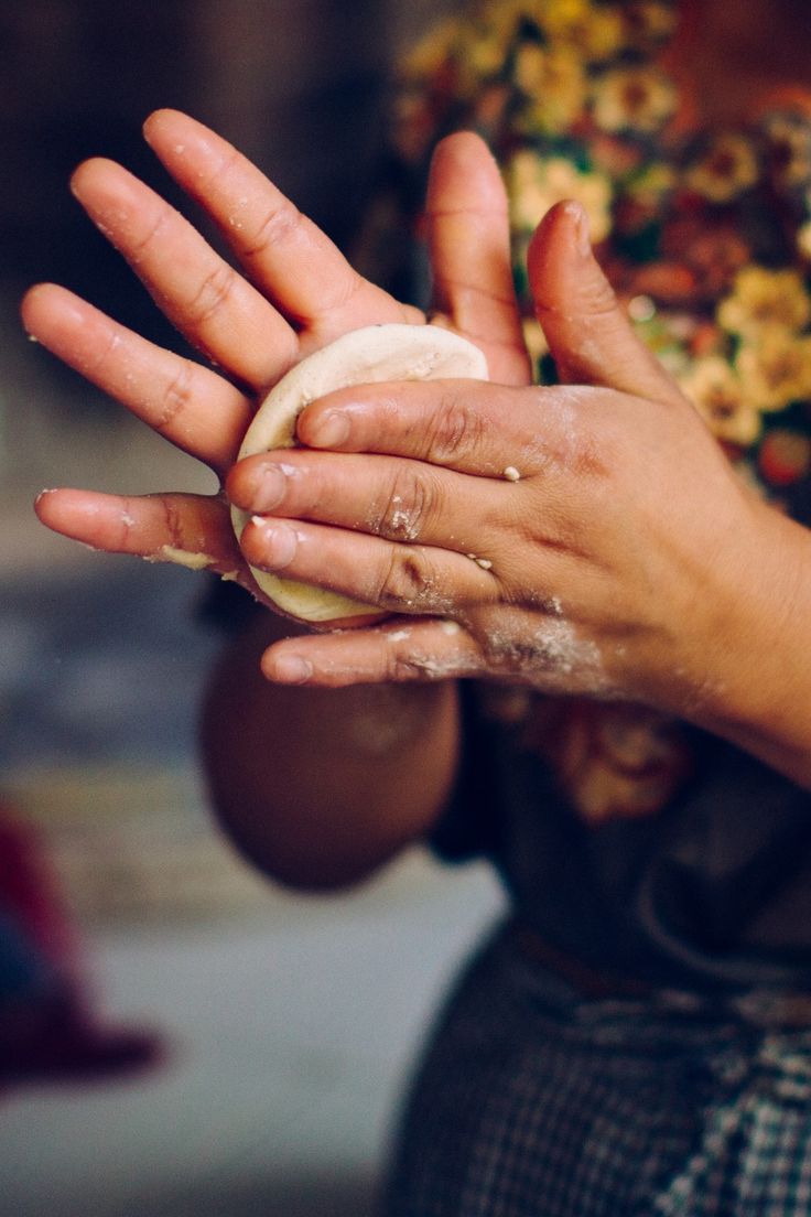Hands shaping a fresh corn tortilla by hand